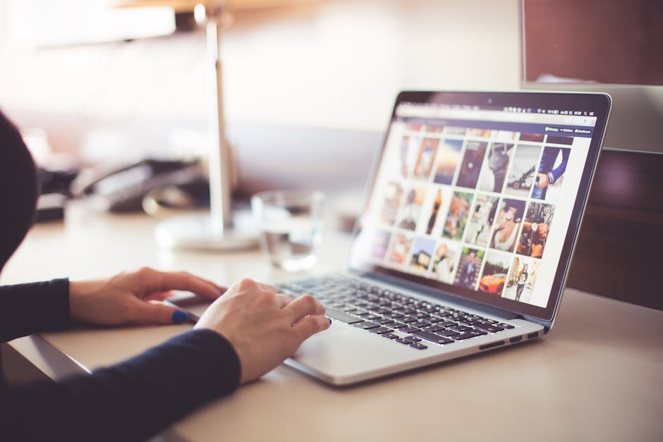 Close-up of hands typing on a laptop with an image gallery open on the screen